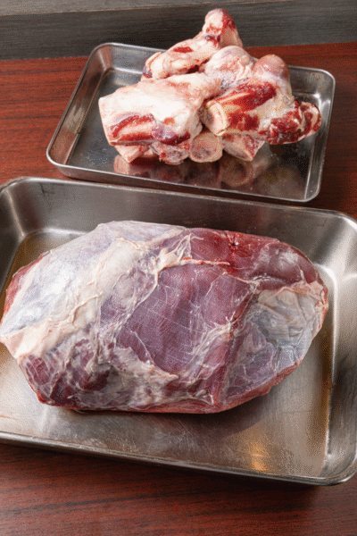 エゾ鹿肉はシンタマ（写真）やスネなど仕入れにより変わる。奥は鹿骨。