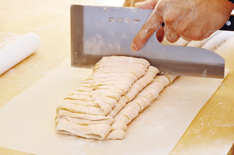 純手打ちの自家製極太麺。加水率50％以上の超多加水麺で、もちもちちゅるんとした食感。