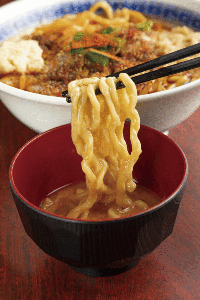 「チーメン」をしっかり手揉みして茹でる。麺を生卵につけるすき焼きスタイルも人気。